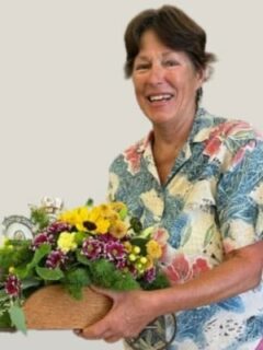 A woman with a colorful shirt holding a basket of flowers