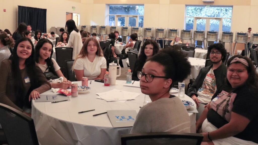 High school students sitting at a round table in a conference room