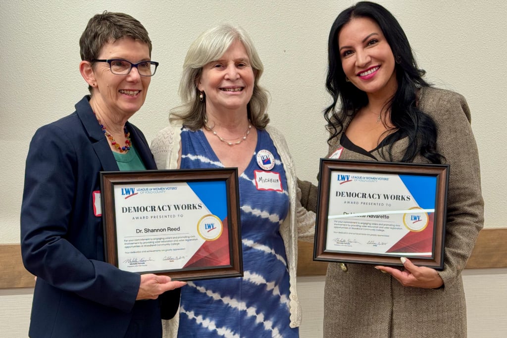 Three women, two holding Award certificates