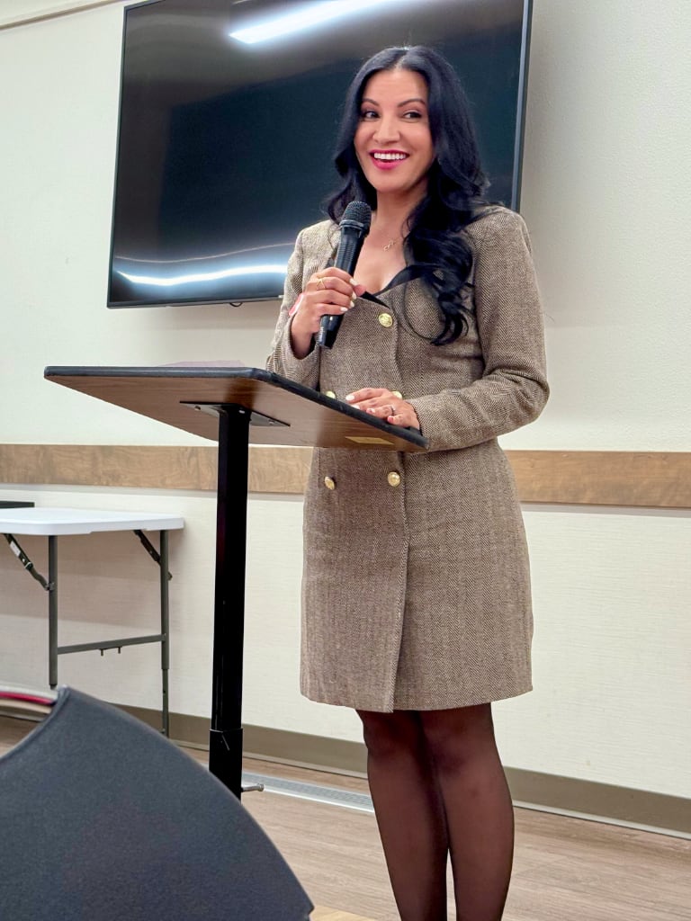 Dr. Lizette Navarette at the podium smiling to meeting attendees