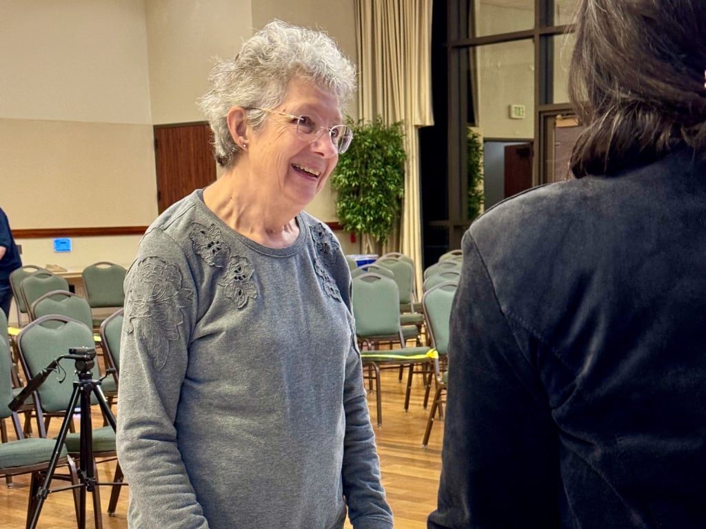 A silver-haired woman talking with another person