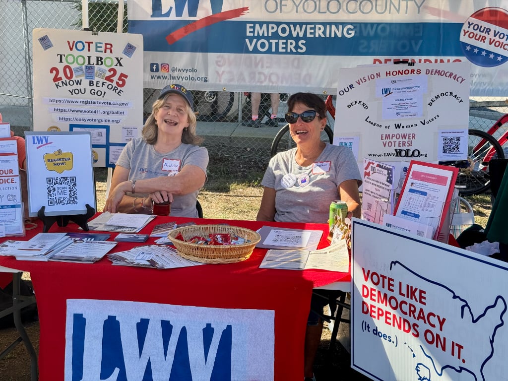 Two League members women surrounded by voting info and signes