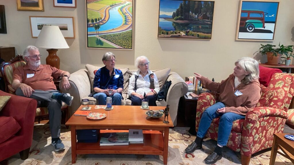 Three people in a living room listening to LWVYC President, Michelle Famula