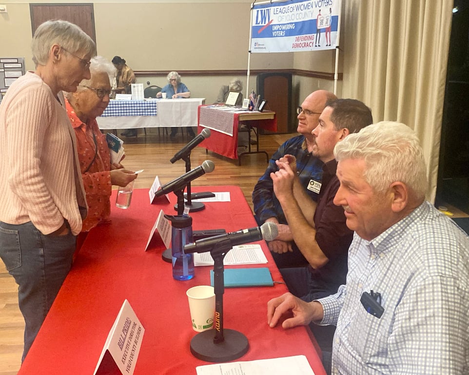 An elderly couple speak to the panel members seated behind table