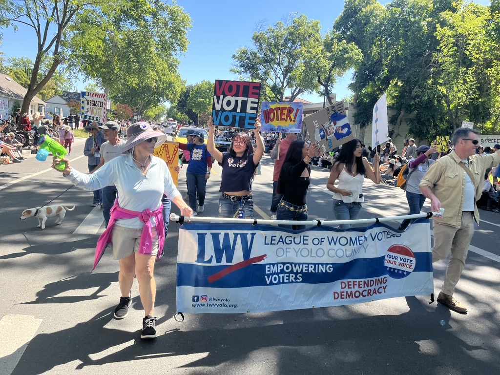 LWV of Yolo County friends and members holding a banner and signs on a Davis street