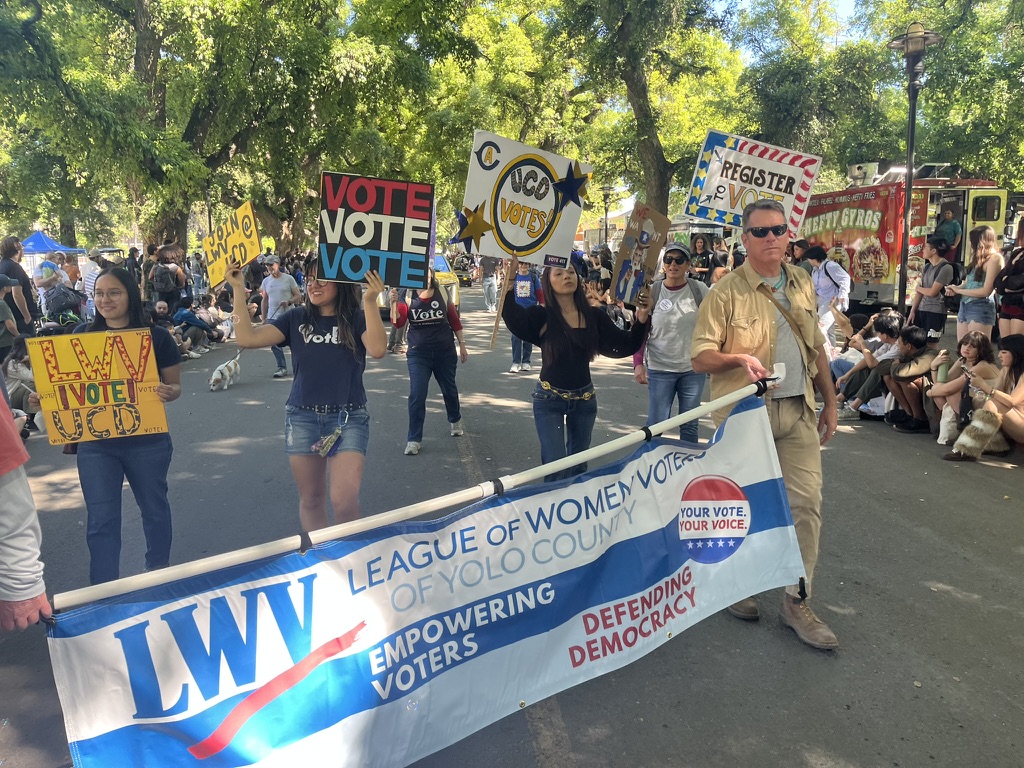 LWV of Yolo County friends and members holding a banner and signs on a Davis street