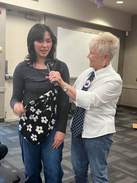 A LWV leader holding microphone for high school student winner
