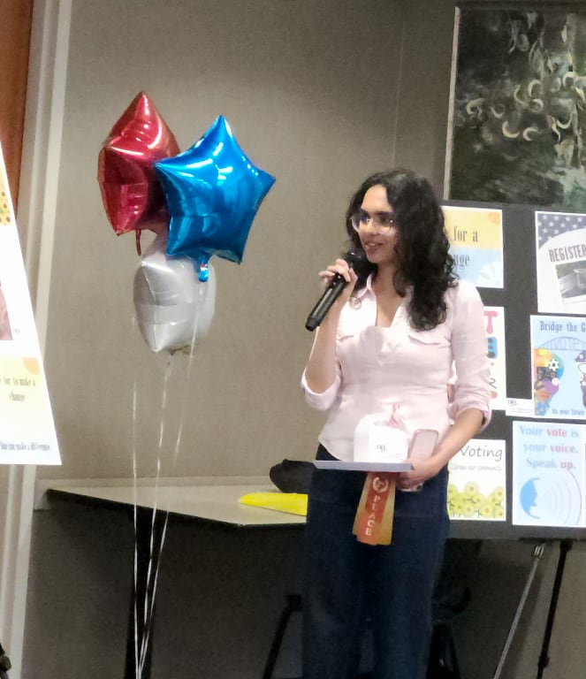A high school student speaking into a microphone about her 2nd place prize