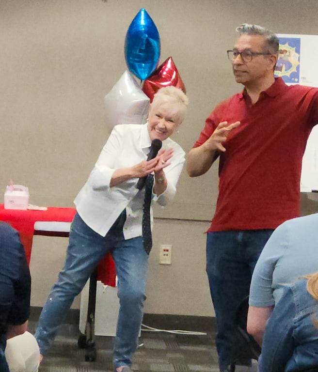 A woman and a man laughing at an event with balloons in the background