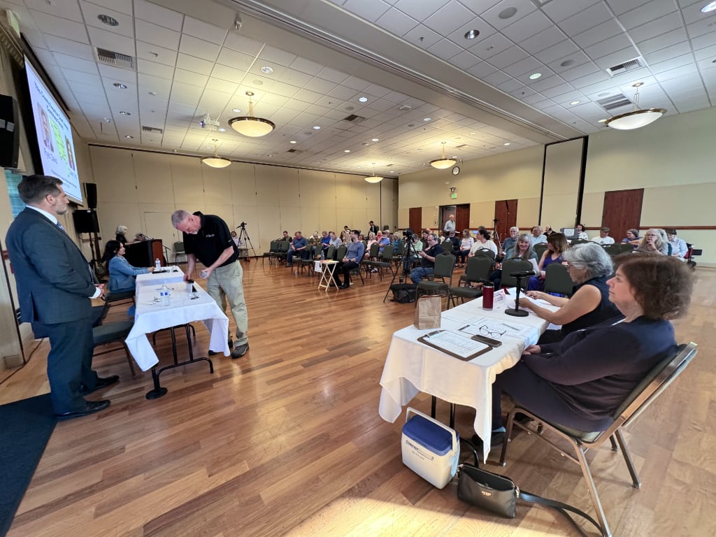 A wide-angle photo of audience, moderators and candidates getting ready for forum
