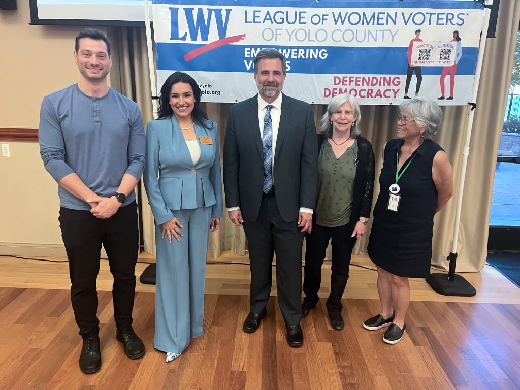 Two men and three women under a LWV's banner